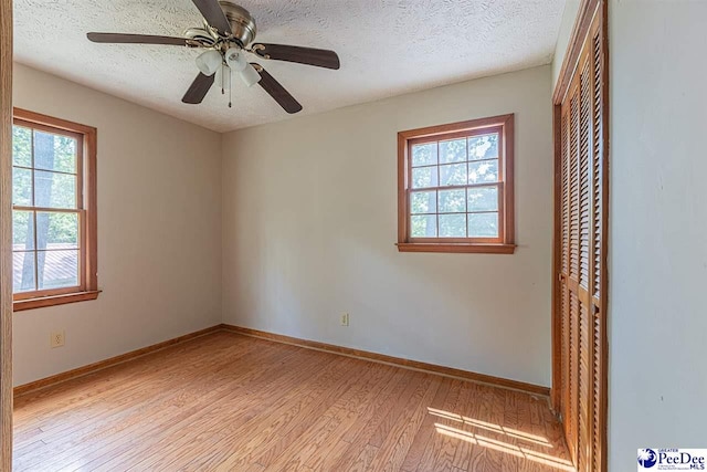 unfurnished bedroom featuring ceiling fan, a textured ceiling, light hardwood / wood-style floors, and a closet