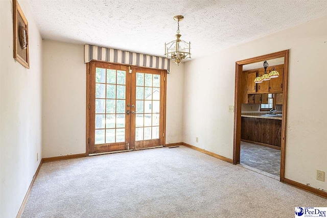 unfurnished room featuring carpet flooring, sink, a notable chandelier, a textured ceiling, and french doors