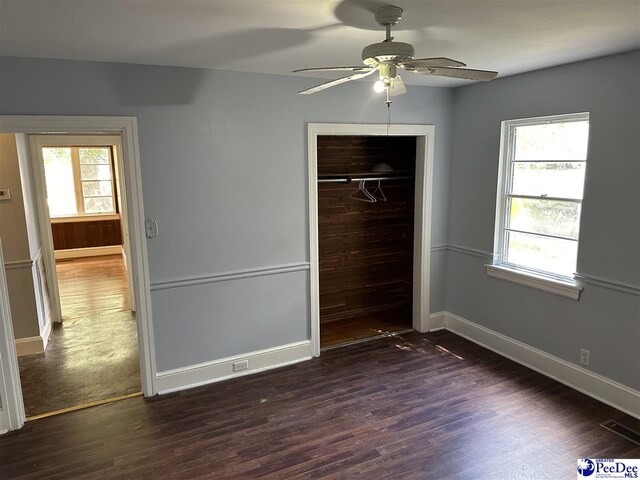 unfurnished bedroom with dark wood-type flooring, ceiling fan, and a closet