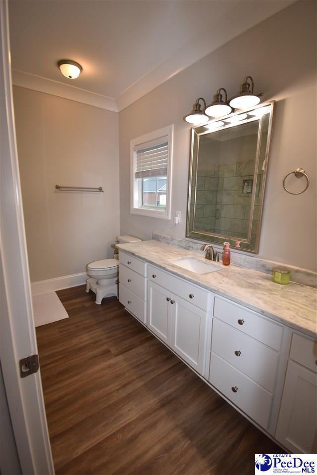 3804 Beckford St, Florence, SC 29501 - bathroom with wood finished floors, vanity, toilet, crown molding, and tiled shower