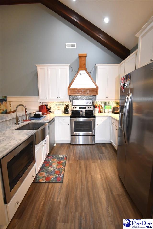 3804 Beckford St, Florence, SC 29501 - kitchen featuring appliances with stainless steel finishes, custom range hood, beam ceiling, a sink, and white cabinets