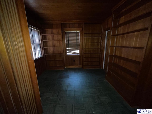 unfurnished room with dark parquet flooring, wooden ceiling, and wooden walls