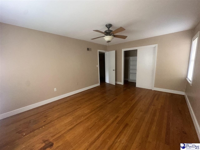 unfurnished bedroom featuring dark hardwood / wood-style floors, ceiling fan, and a closet