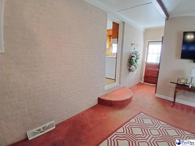 hallway with brick wall, ornamental molding, and carpet