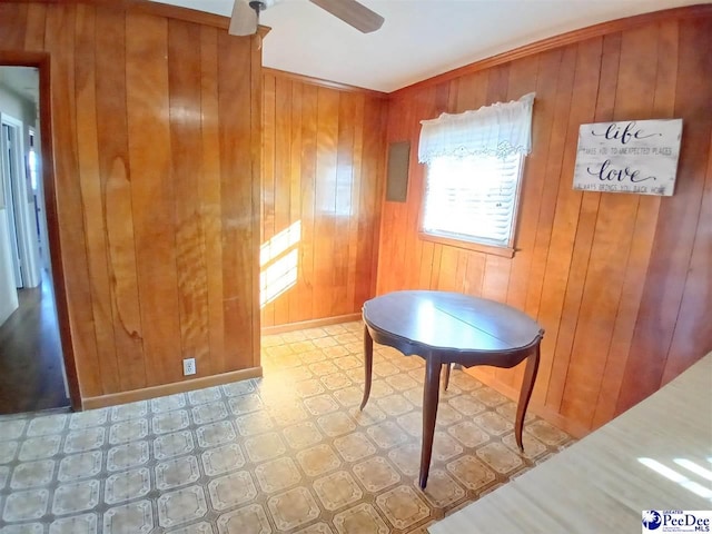 unfurnished dining area with ceiling fan and wood walls