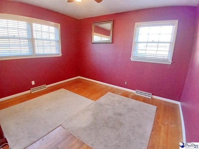 spare room featuring hardwood / wood-style floors, a healthy amount of sunlight, and ceiling fan