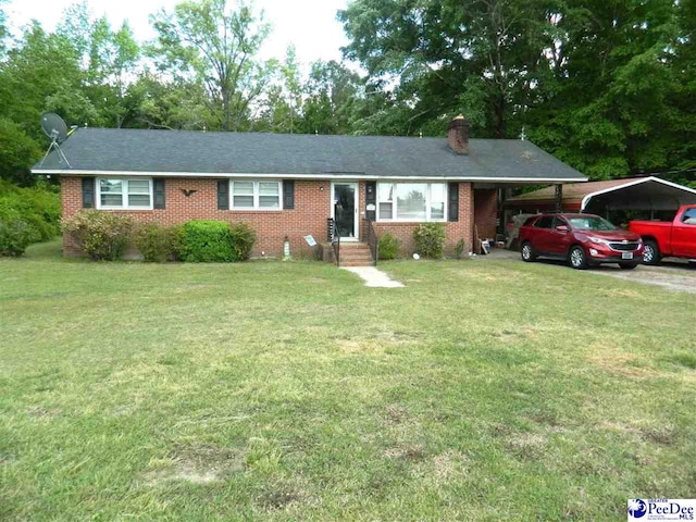ranch-style house featuring a chimney, brick siding, a carport, and a front yard
