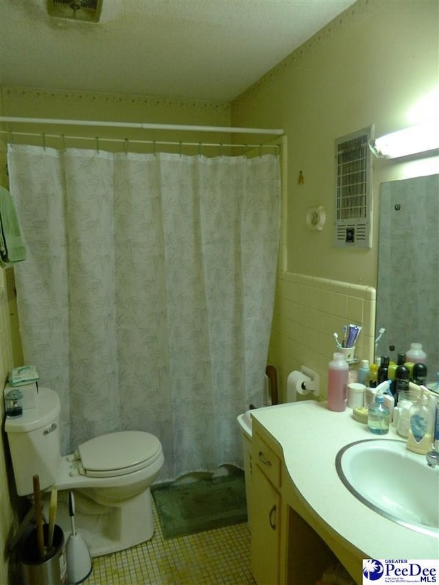 bathroom with tile patterned floors, vanity, tile walls, a wainscoted wall, and toilet