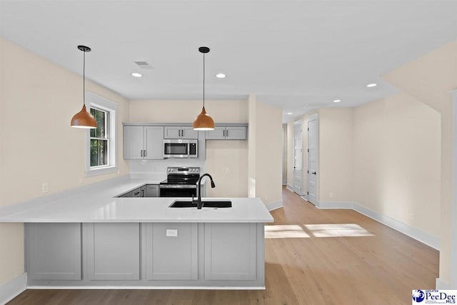 125 E Pine St, Florence, SC 29506 - kitchen with stainless steel appliances, a peninsula, light countertops, light wood finished floors, and recessed lighting