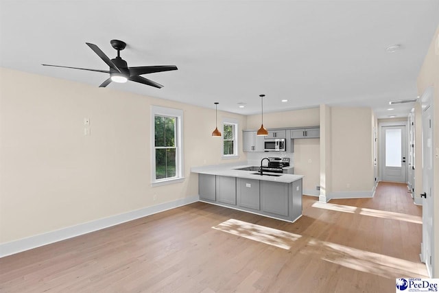 125 E Pine St, Florence, SC 29506 - kitchen with stainless steel microwave, a peninsula, light countertops, light wood-style floors, and decorative light fixtures