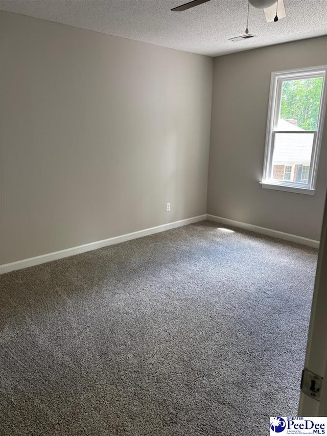 carpeted spare room with baseboards, visible vents, ceiling fan, and a textured ceiling