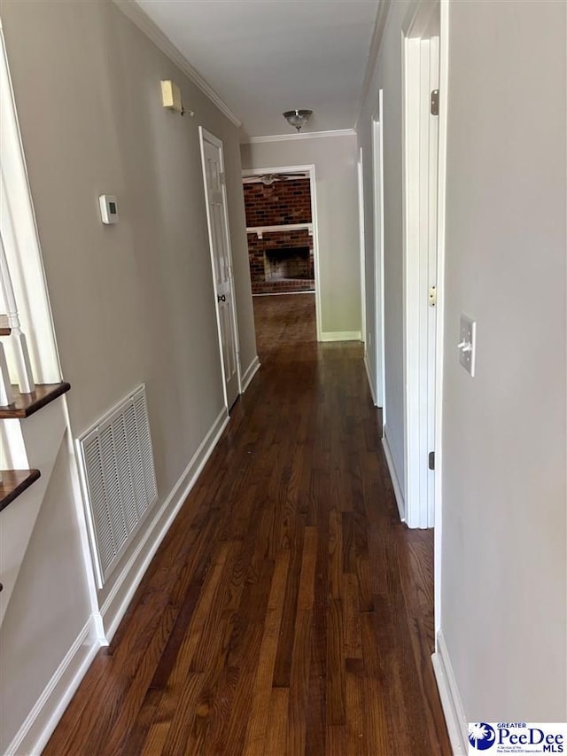 corridor featuring dark wood-style flooring, visible vents, and crown molding