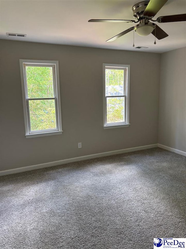 carpeted empty room featuring visible vents, ceiling fan, and baseboards