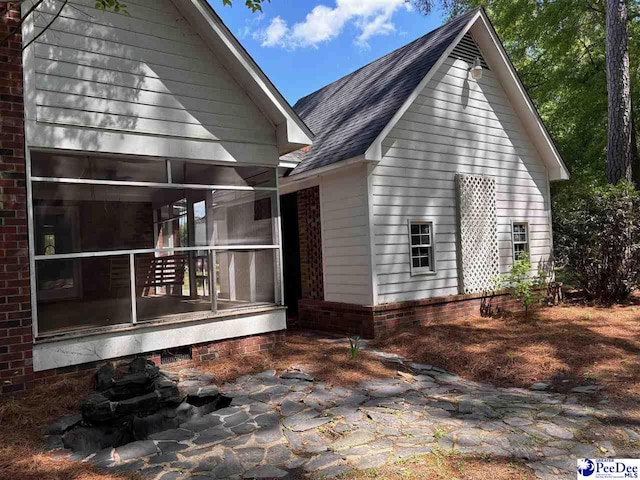 back of property featuring roof with shingles and a sunroom