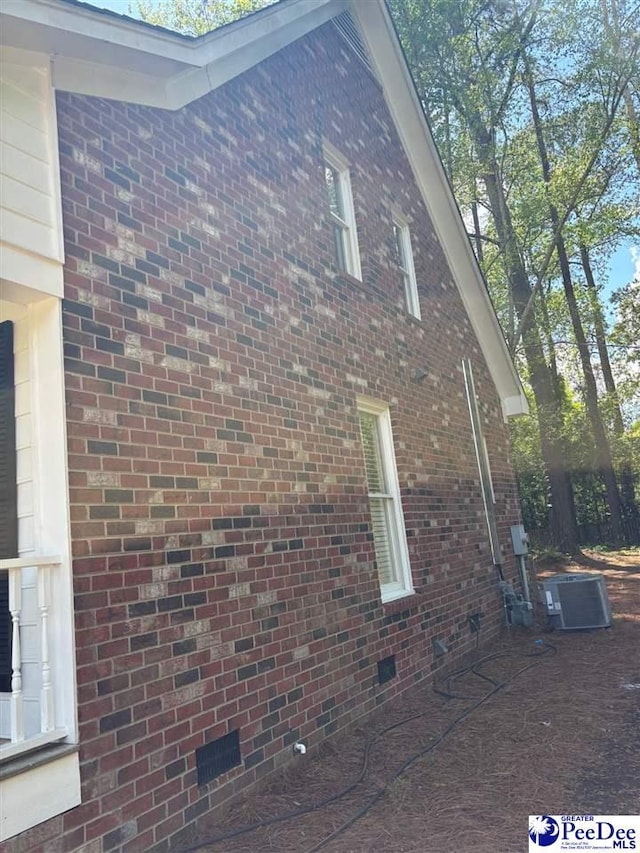 view of side of home featuring cooling unit, crawl space, and brick siding