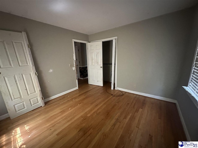 unfurnished bedroom with baseboards and wood finished floors