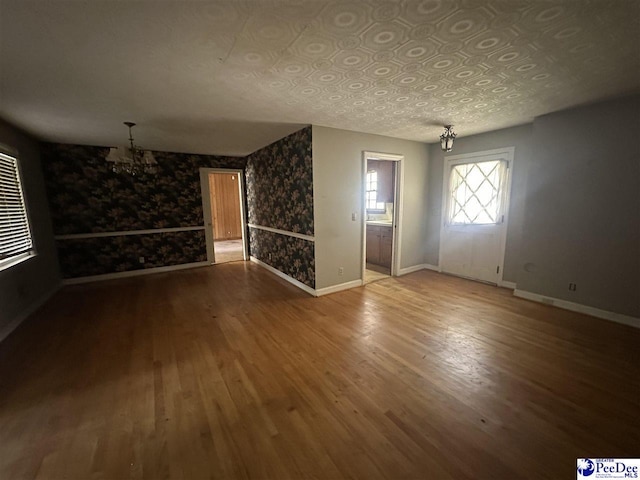 interior space with baseboards, wood finished floors, and a chandelier