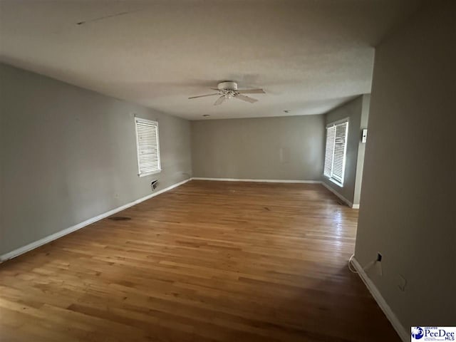 spare room featuring a ceiling fan, baseboards, and wood finished floors