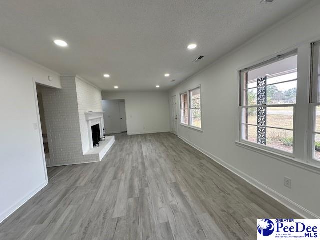 unfurnished living room featuring a fireplace, a textured ceiling, and hardwood / wood-style flooring