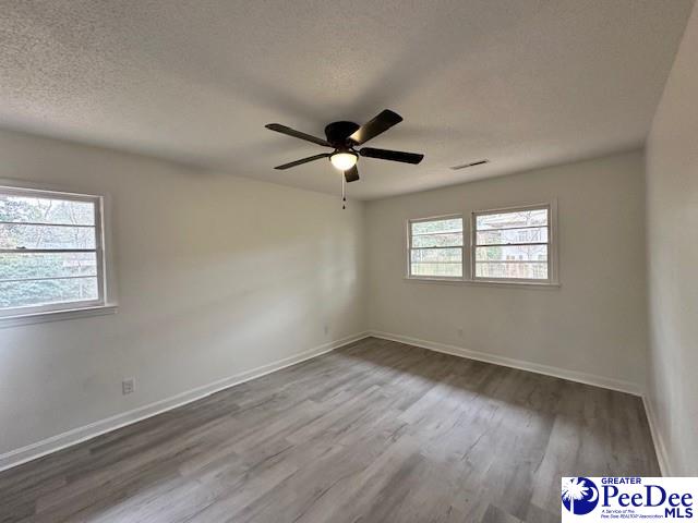 empty room with a textured ceiling, hardwood / wood-style flooring, and ceiling fan