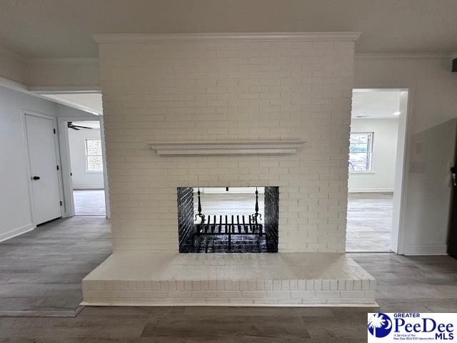 details with a brick fireplace, crown molding, ceiling fan, and wood-type flooring