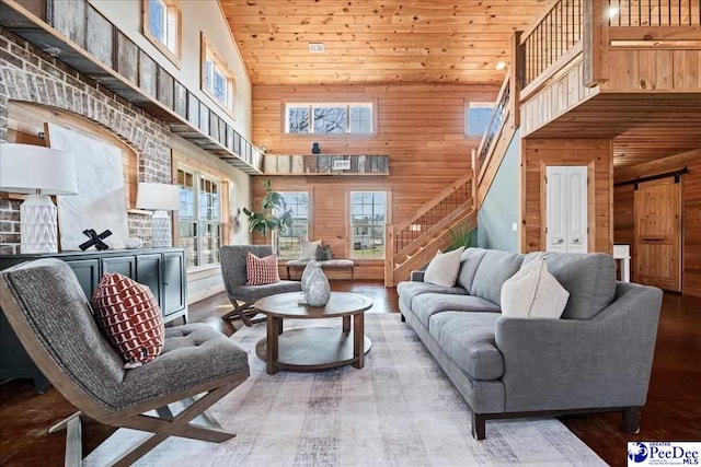 living room with a wealth of natural light, wooden ceiling, wood walls, and stairs