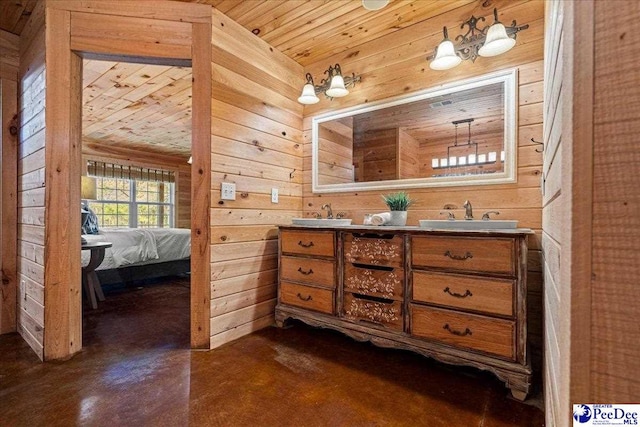 bathroom with ensuite bathroom, finished concrete floors, wood ceiling, a sink, and wooden walls