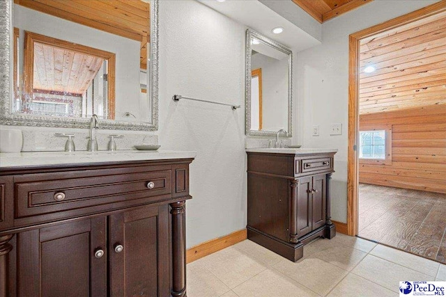 bathroom featuring a sink, baseboards, two vanities, and tile patterned floors