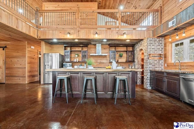 kitchen with open shelves, wall chimney range hood, appliances with stainless steel finishes, and wooden walls