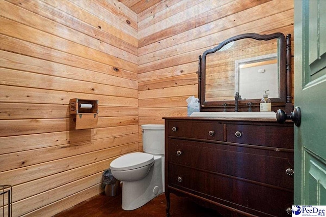 half bath featuring wood walls, vanity, and toilet