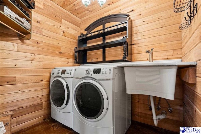 laundry area with laundry area, separate washer and dryer, and wood walls