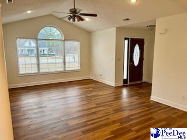 foyer featuring a textured ceiling, vaulted ceiling, dark hardwood / wood-style floors, and ceiling fan