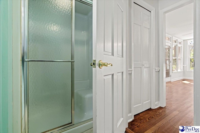 bathroom with baseboards, an enclosed shower, and wood finished floors