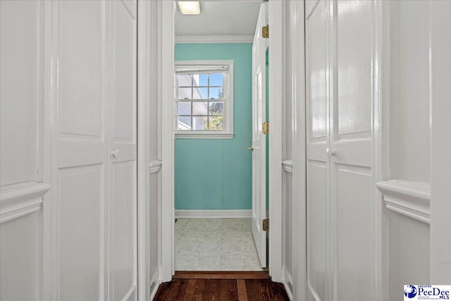 corridor with baseboards, ornamental molding, and dark wood-type flooring