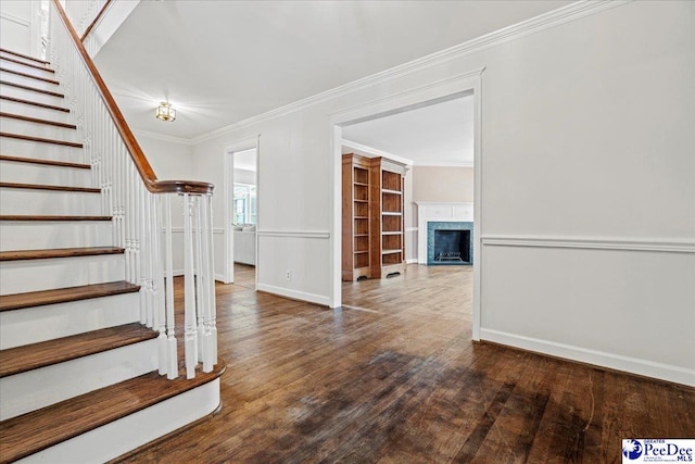 interior space with baseboards, crown molding, a premium fireplace, and wood finished floors