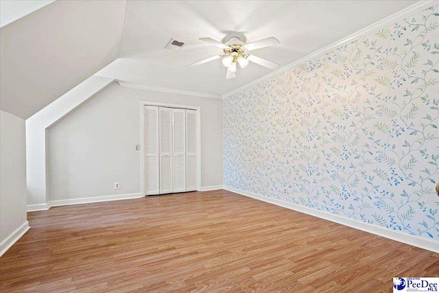 additional living space featuring wallpapered walls, baseboards, visible vents, a ceiling fan, and wood finished floors