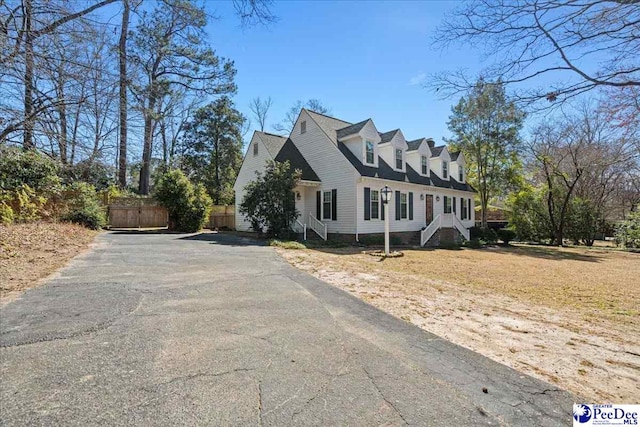 view of side of property featuring stairs, fence, and aphalt driveway