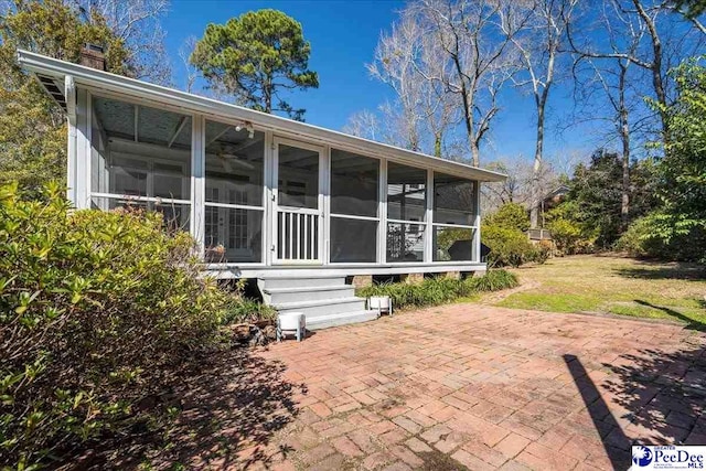 rear view of house with a sunroom, a patio area, and a chimney