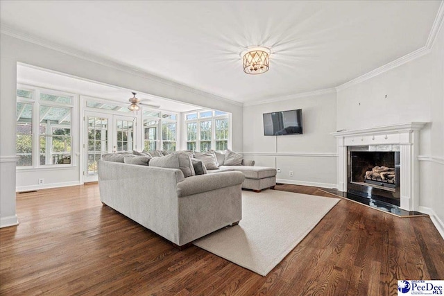 living area featuring dark wood-style floors, a fireplace with flush hearth, plenty of natural light, and crown molding