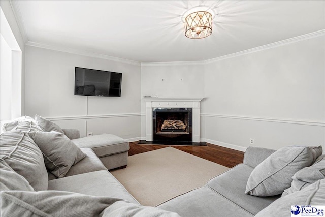 living area with crown molding, a premium fireplace, baseboards, and wood finished floors