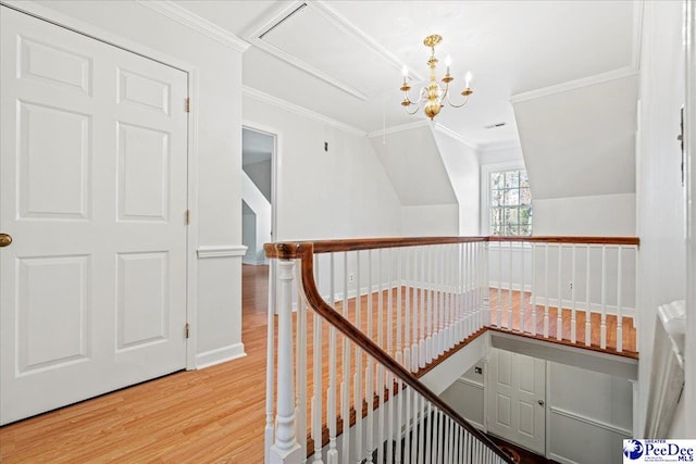 corridor with baseboards, ornamental molding, wood finished floors, an inviting chandelier, and an upstairs landing