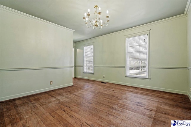 unfurnished room featuring baseboards, visible vents, ornamental molding, wood finished floors, and a chandelier