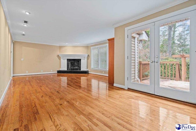 unfurnished living room with a wealth of natural light, ornamental molding, french doors, and light wood-type flooring