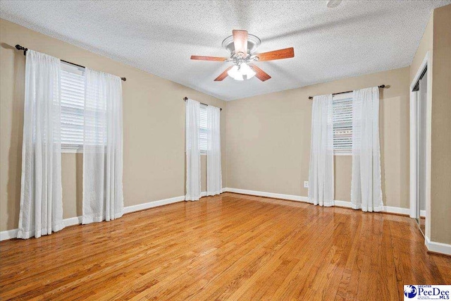 spare room with ceiling fan, light hardwood / wood-style floors, and a textured ceiling