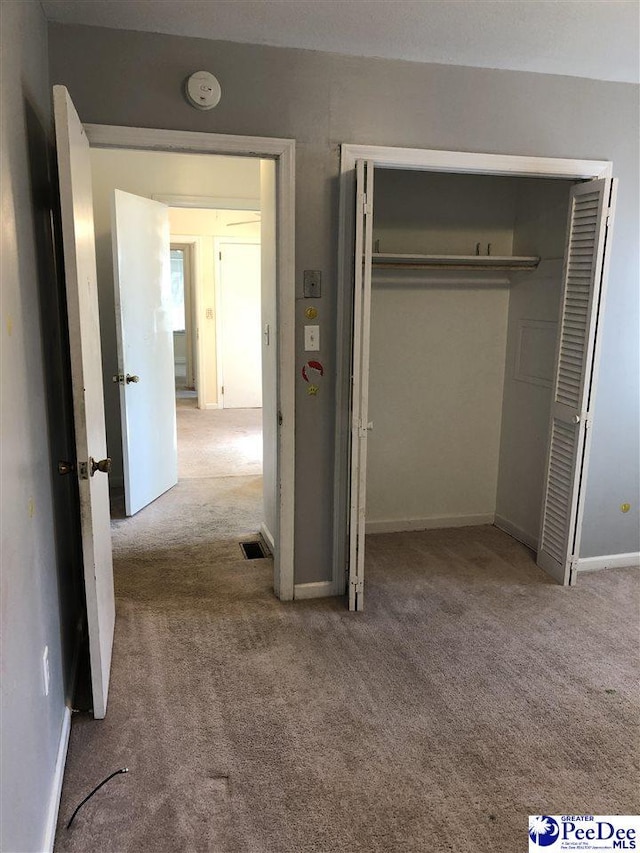 unfurnished bedroom featuring carpet floors, a closet, visible vents, and baseboards