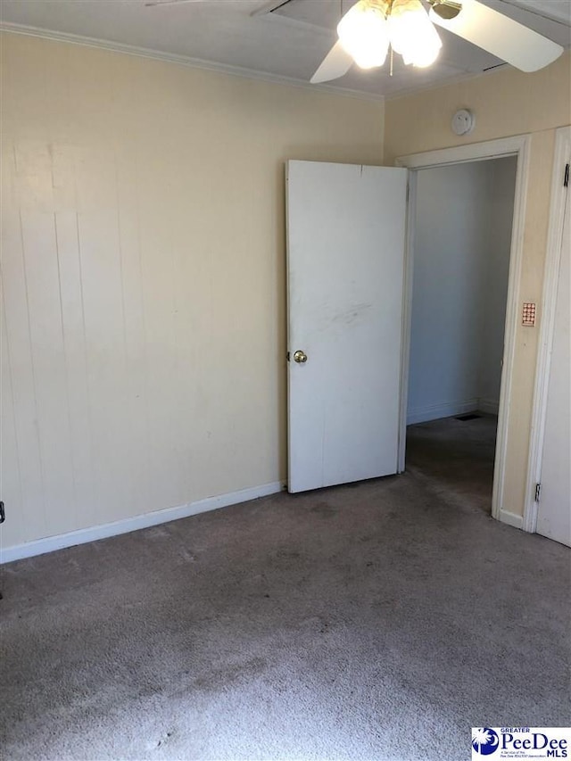 carpeted empty room featuring baseboards, a ceiling fan, and crown molding