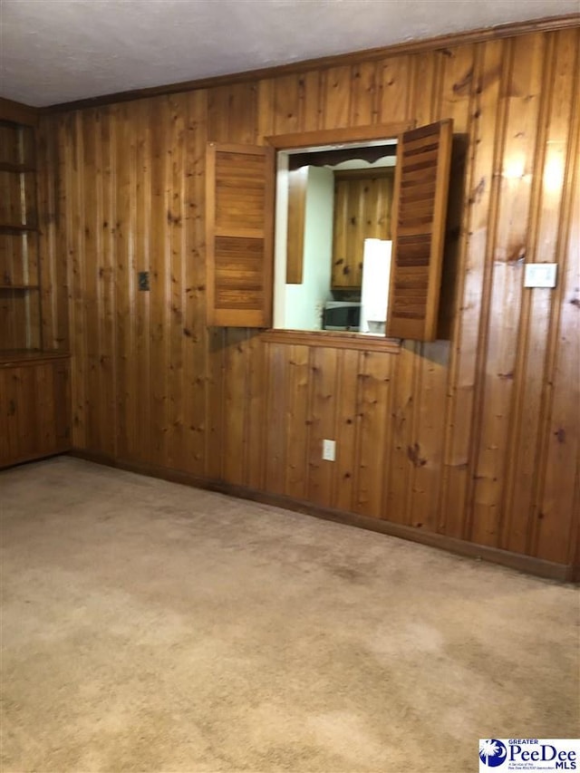 unfurnished room with ornamental molding, light colored carpet, and wooden walls