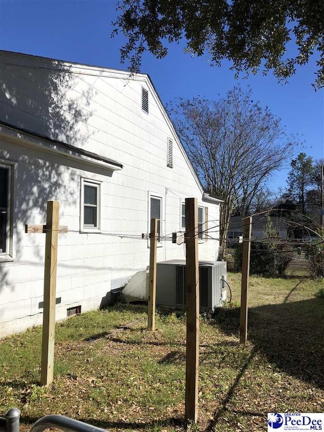 back of house with central AC unit and a lawn