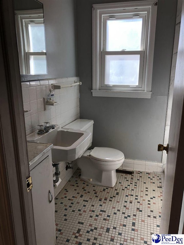 bathroom with backsplash, tile patterned flooring, toilet, and baseboards