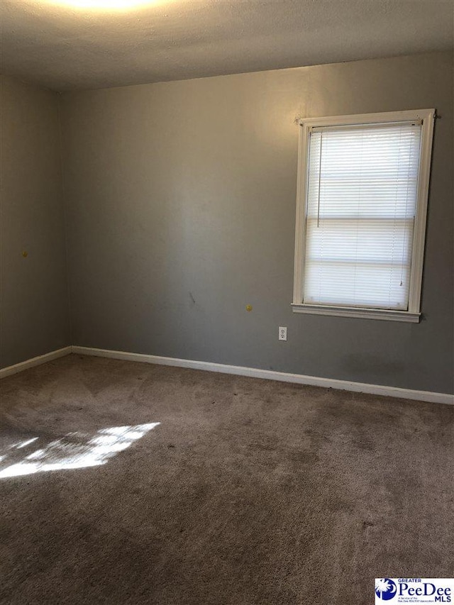 carpeted empty room featuring a textured ceiling and baseboards